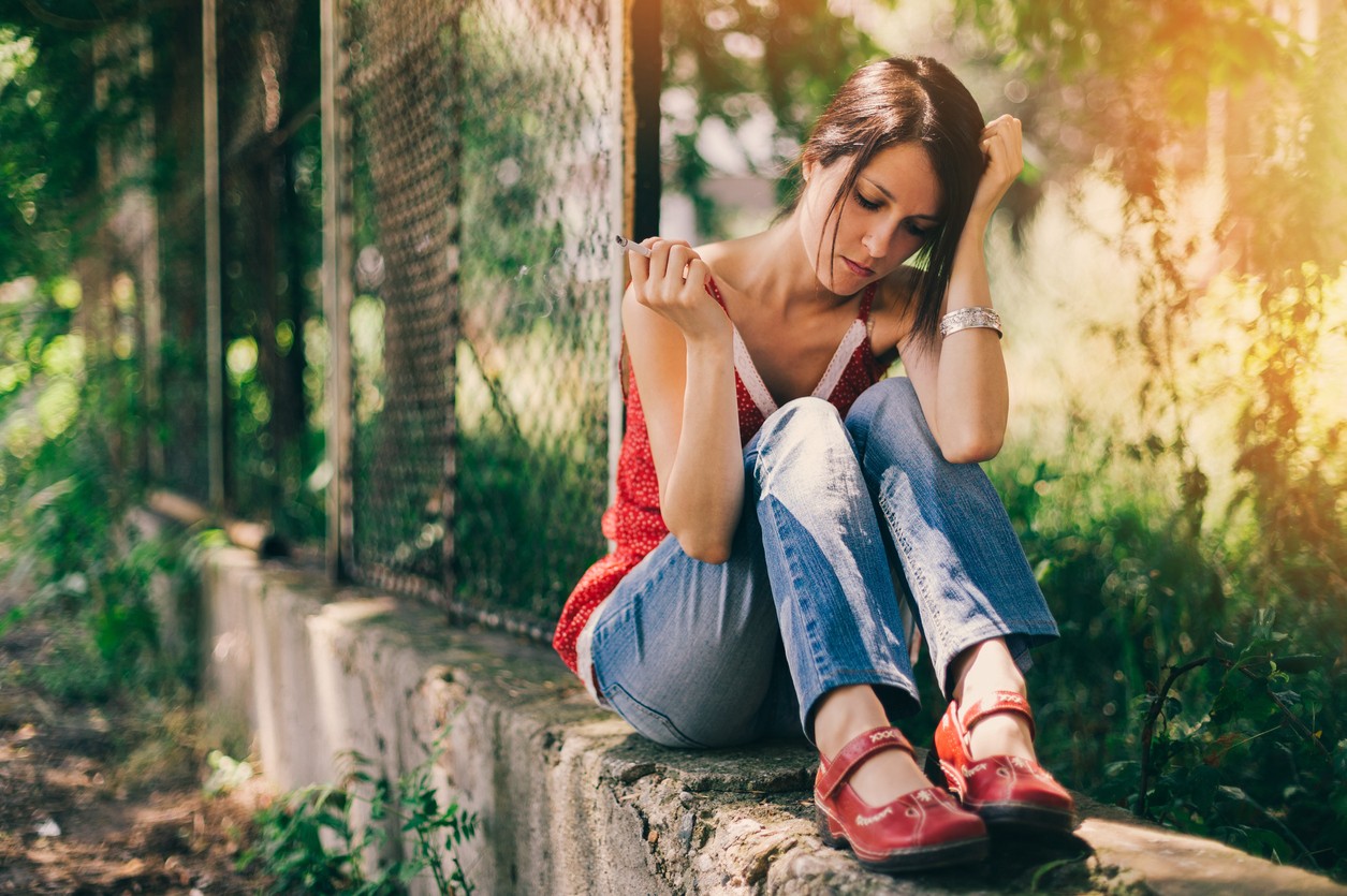 Depressed girl at the school yard smoking cigarette