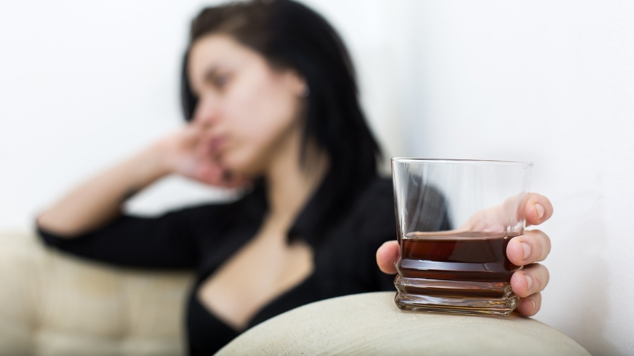 Sad girl holding glass of scotch